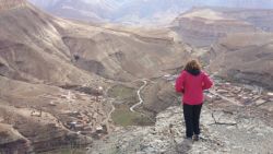 Persona con chaqueta roja contemplando un valle montañoso  